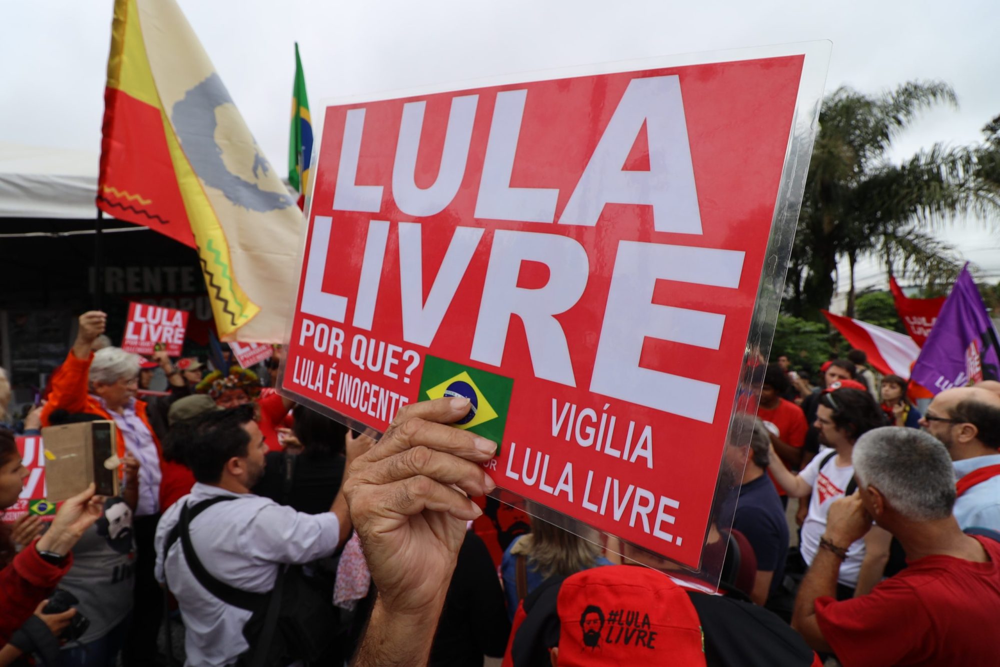 A man holds a sign in front of the Curitiba federal prison where former president Luiz Inacio Lula da Silva is behind held. The sign reads: “Free Lula. Why? Because he's innocent.”
